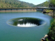 Az USA-beli Monticello Dam gátnál található hátborzongató jelenség nem a természet, hanem az ember műve. A 22 méter átmérőjű lefolyó egy több száz méter hosszú csövön át vezeti a vizet a gát másik oldalára. 