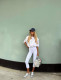 Fémes hatású sneakerrel

A capri nadrág nemcsak elegáns, hanem sportosan is elképesztően trendi tud lenni – ezt bizonyítja ez a letisztult, athleisure ihletésű szett is. A fehér capri leggings friss és modern hatást kelt, különösen fémes árnyalatú sneakerekkel párosítva, amelyek egy kis futurisztikus csavart adnak az outfitnek. Ez a kombináció tökéletes választás lehet rohanós hétköznapokra, utazáshoz vagy egy laza városi naphoz, amikor egyszerre fontos a kényelem és a stílus. A baseballsapka és a könnyed, oversized felső tovább erősíti a sportos hangulatot, miközben a capri nadrág nőiesebb és kifinomultabb marad, mint egy klasszikus biciklisnadrág vagy melegítő.